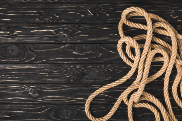 top view of brown nautical rope on dark wooden surface  - Foto, Bild