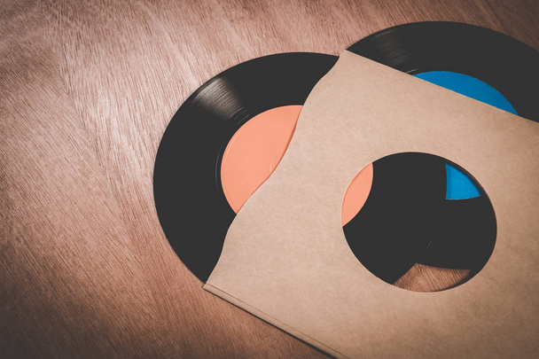 Vieux disques vinyles vintage sales avec de la poussière dans les manches sur une table en bois. Ancien disque de vinyle avec couvercle sur la vieille table
. - Photo, image