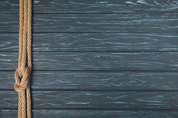 верхний вид фона с коричневой морской верёвкой с узлом на деревянных досках
 - Фото, изображение