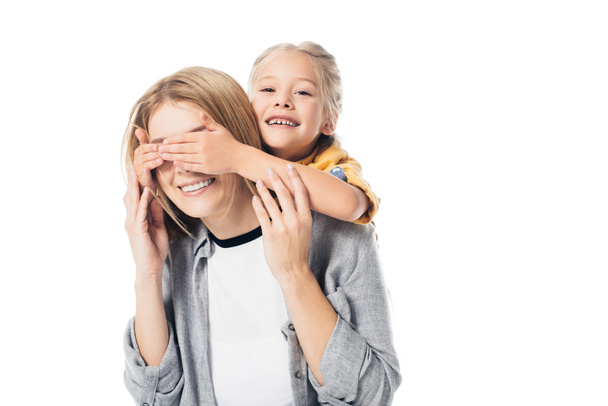 portrait of adorable kid covering mothers eyes to surprise her isolated on white - Foto, afbeelding