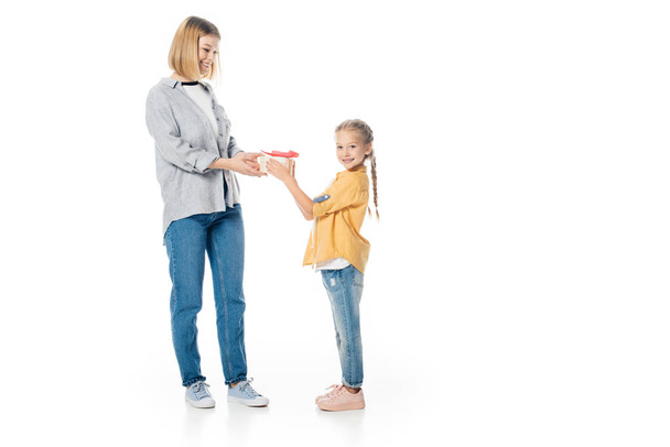 little daughter giving wrapped gift to mother isolated on white, mothers day holiday concept - Fotó, kép