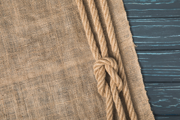 top view of brown nautical rope with knot on sackcloth  - Photo, image
