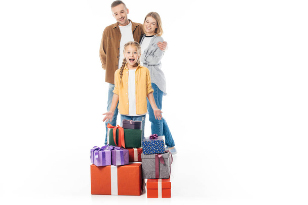 excited kid with pile of wrapped gifts and parents behind isolated on white - Фото, изображение