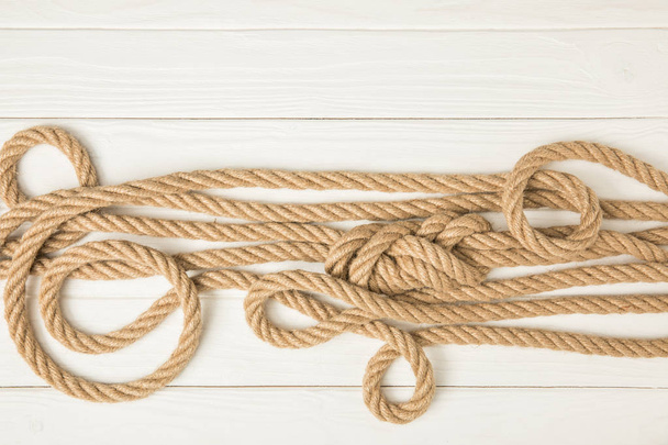 Draufsicht auf braun geknüpfte nautische Seile auf weißer Holzoberfläche - Foto, Bild