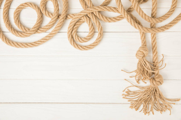 top view of brown nautical knotted rope on white wooden background - Fotoğraf, Görsel