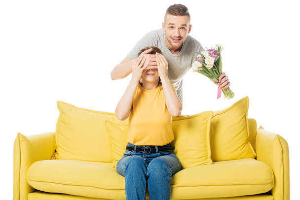 man with bouquet of tulips covering wifes eyes to surprise her isolated on white - Fotografie, Obrázek