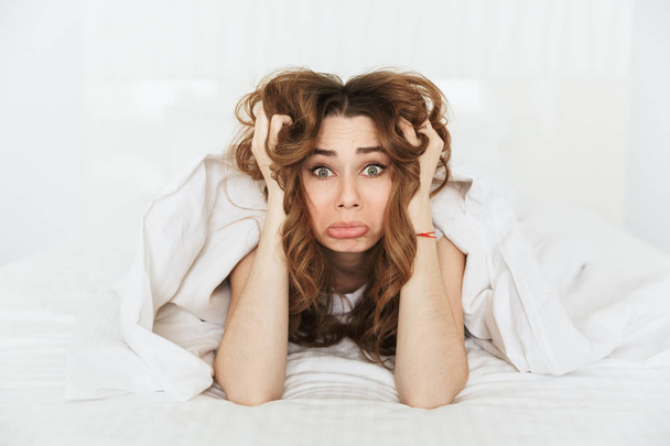 Portrait of an upset young woman lying in bed u - Zdjęcie, obraz