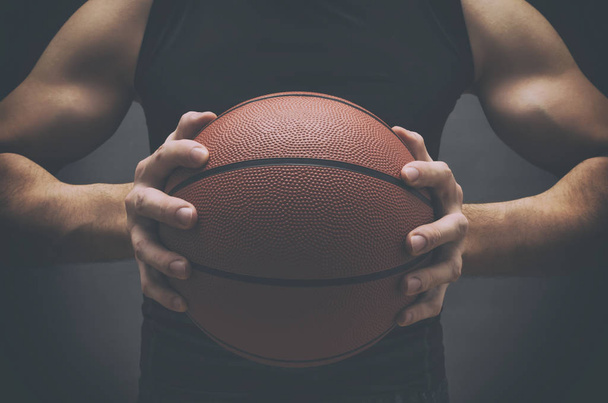 Mužský basketbalový hráč s míčem přes tmavé pozadí. - Fotografie, Obrázek