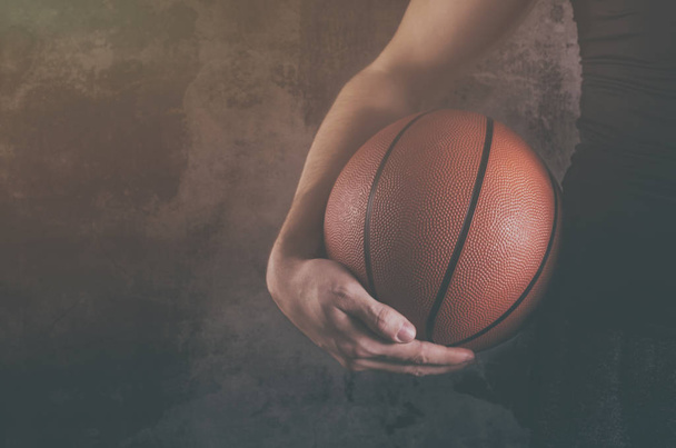 Male basketball player with a ball over dark background. - Foto, imagen