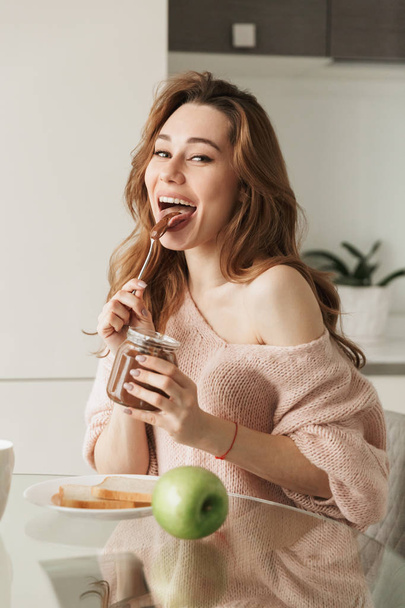 Portrait of a delighted young woman having tasty breakfast - Valokuva, kuva