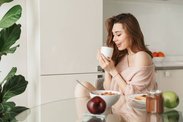 Portrait of a cheerful young woman having healthy breakfast - Foto, Bild
