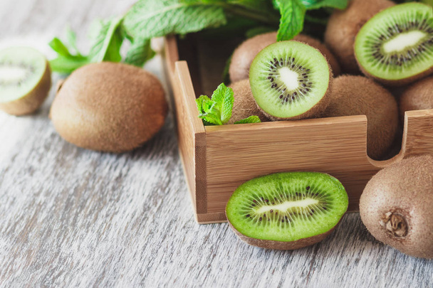 Green kiwis and mint leaves in the wooden tray - Foto, afbeelding