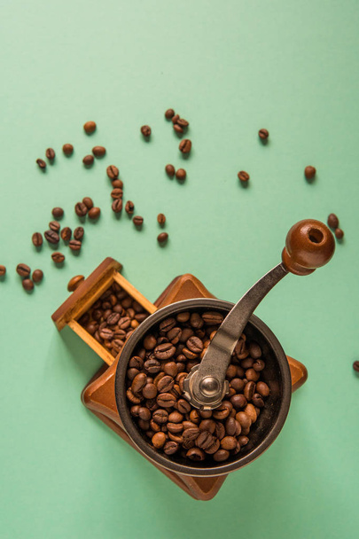Coffee beans in a hand-held coffee grinder on a tender green bac - Photo, Image