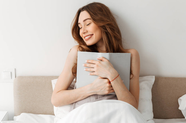 Portrait of beautiful smiling woman resting in comfortable bed a - Фото, зображення