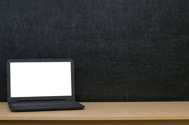 Teacher or student desk table. Education background. Education mockup concept. Laptop computer with blank screen on blackboard (chalkboard) background. - Foto, imagen