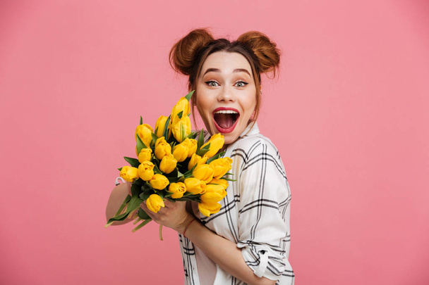 Portrait of an excited young girl holding yellow tulips - Photo, image