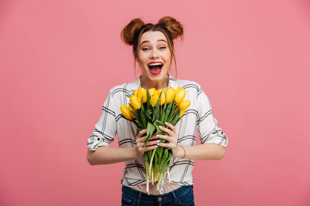 Portrait of an excited young girl holding yellow tulips - Fotó, kép