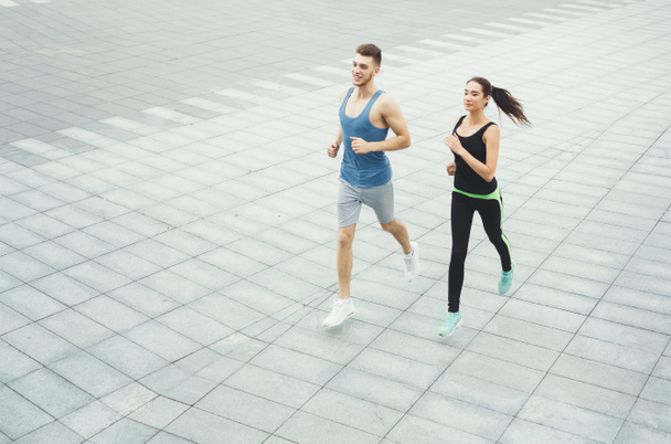 Young woman and man jogging in city copy space - 写真・画像