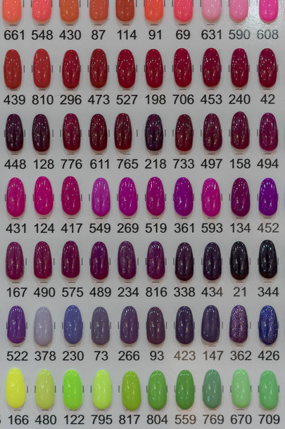 Conjunto de diferentes cores de esmalte na paleta na loja de cosméticos. Ampla gama de coloração de unhas
. - Foto, Imagem