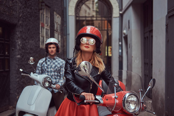A handsome man and a sexy stylish girl are walking with retro Italian scooters along the old streets of the city. - Photo, Image