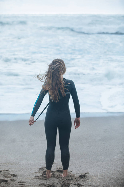 a young woman stretching before swim wearing wetsuit on the seas - Photo, image