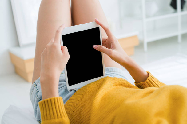 Jovem mulher asiática usando tablet simular tela preta em branco em seu quarto sozinho, deslizando-o com o dedo no dia de luz quente sol. Mulher furto no tablet no quarto
. - Foto, Imagem