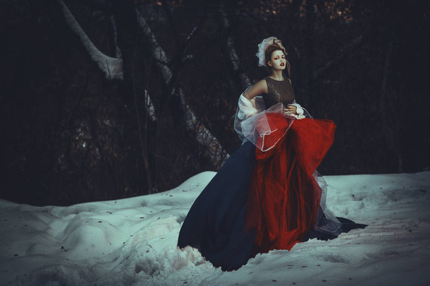 Beautiful model with creative makeup is posing in a winter forest - Fotó, kép