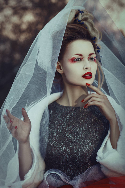 Beautiful model with creative makeup is posing in a winter forest - Φωτογραφία, εικόνα