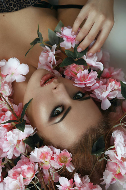 Красива блондинка модель емоційно позує з квітами
 - Фото, зображення