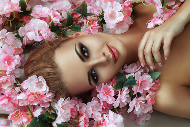 The beautiful blonde model is emotionally posing with flowers - Фото, изображение