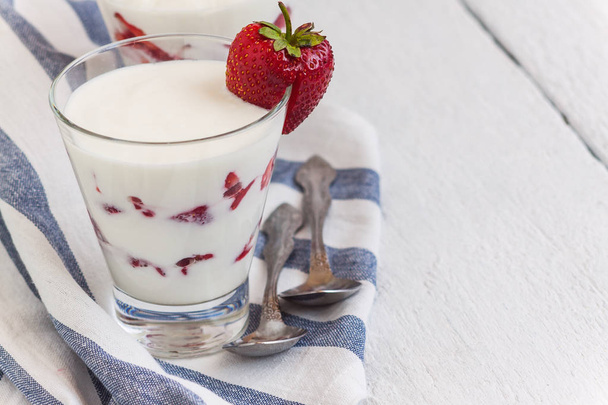 Couches de yaourt et de fraises dans un verre sur une bande bleue
 - Photo, image