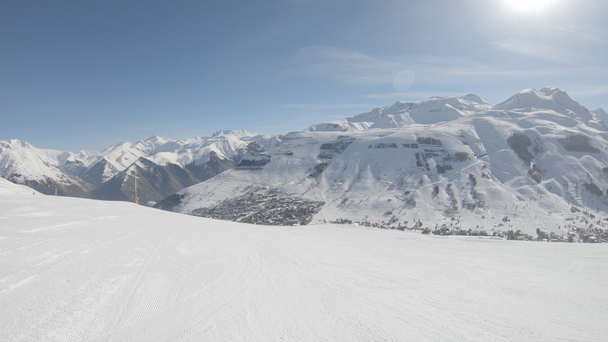 Narciarz szybko zejść na trasie narciarskiego przy słonecznej pogodzie przeciwko zboczach gór - Materiał filmowy, wideo