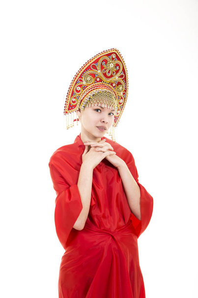 Portrait of smiling girl in kokoshnik (headdress) and red dress on white background. - 写真・画像