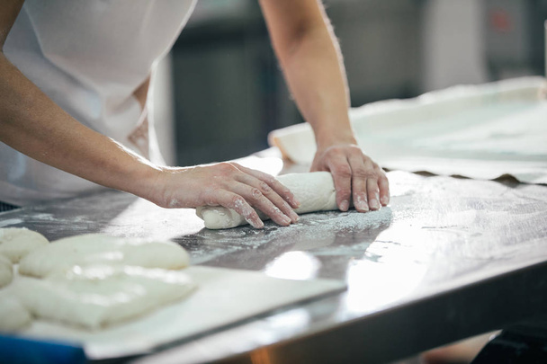 Baker ekmek hazırlanıyor. Hamur yoğurma elinde kapatın. Fırın ekmek üreticileri  - Fotoğraf, Görsel