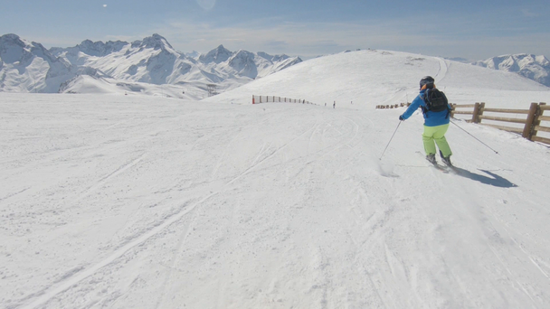 Narciarz alpejski, krótkim huśtawki na nartach na stoku narciarskiego na słoneczne zimowe dni - Materiał filmowy, wideo