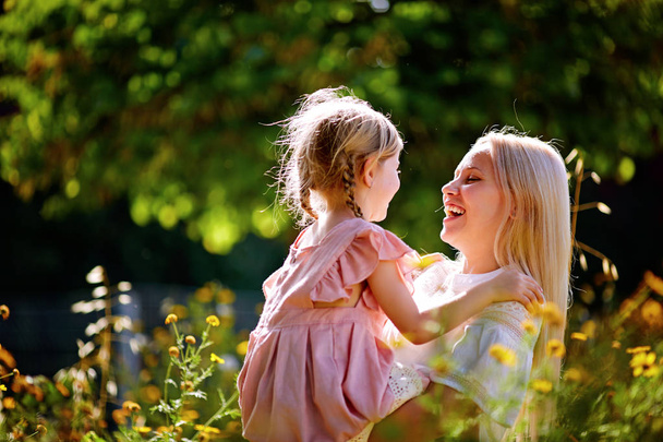 glückliche Mutter mit ihrer Tochter auf dem Feld, gelbe Blumen - Foto, Bild