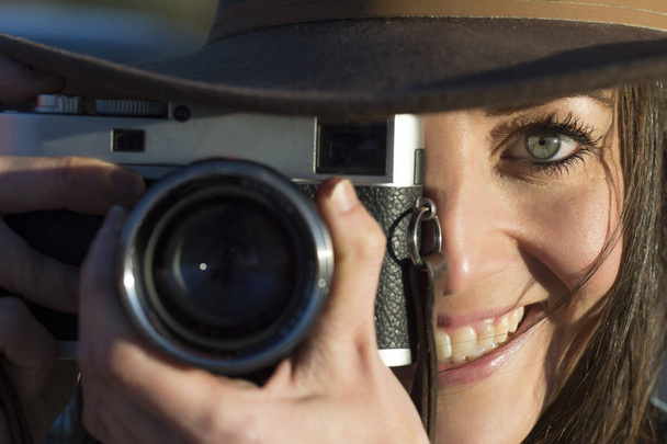 Усміхнена молода жінка використовує камеру, щоб сфотографуватися
. - Фото, зображення