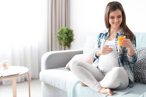 Young pregnant woman holding glass with juice at home - Photo, image