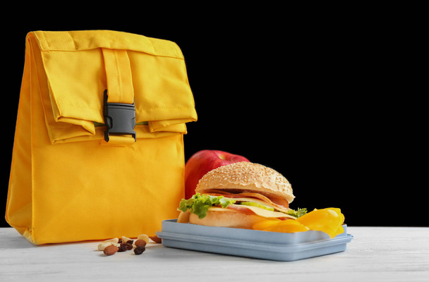 Lunch box with appetizing food and bag on table - Zdjęcie, obraz