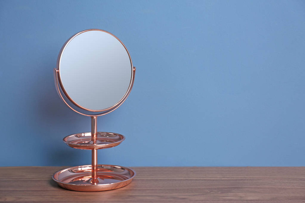 Mirror with accessory holder on table near color wall - Фото, зображення