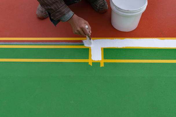 werknemer schilderen de zijlijn op de vloer voor een openlucht stadion - Foto, afbeelding