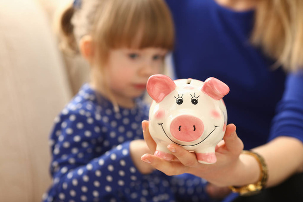 Child little girl arm putting coins into piggybank - Fotó, kép