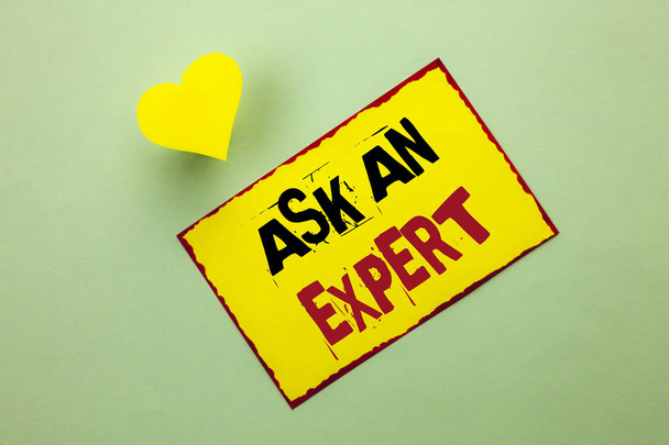 Wortlaut Text fragen Sie einen Experten. Businesskonzept für die Beratung eines Fachmanns, der um Rat bittet, eine Frage auf gelbem Zettelpapier auf dem schlichten Hintergrundherz daneben schreiben. - Foto, Bild
