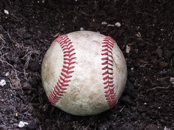 Nahaufnahme Sport Hintergrundbild eines alten verwitterten Leder-Baseball-Legen in einem Haufen braunen Schmutzes zeigt komplizierte Details und rote Schnürsenkel. - Foto, Bild