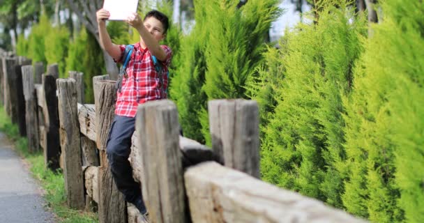 Sorrindo menino fazendo foto selfie no parque de primavera verde
 - Filmagem, Vídeo