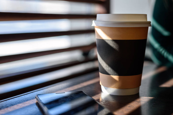 Папір і картон Кубок з кави, капучино, латте чай на дерев'яний стіл в кафе на яскраве сонячне світло з вікна навесні - Фото, зображення