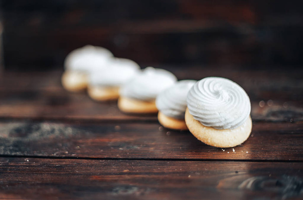 closeup white zephyr cookies lie to the line on wooden background - Photo, Image