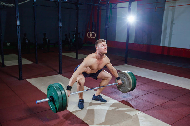 Muscular fitness man preparing to deadlift a barbell over his head in modern fitness center.Functional training.Snatch exercise. - Φωτογραφία, εικόνα