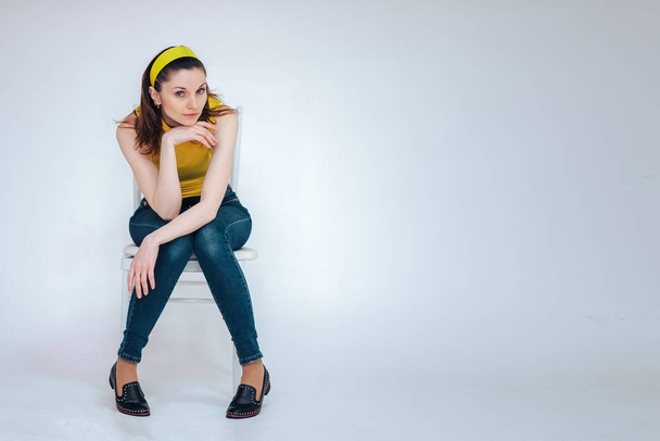 beautiful girl on a chair in a yellow T-shirt on a white background - Foto, Imagen