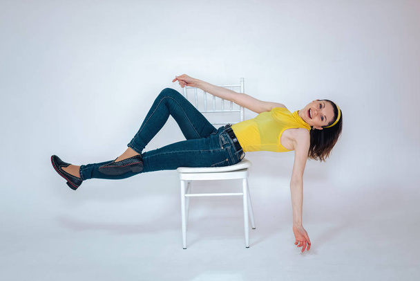 beautiful girl on a chair in a yellow T-shirt on a white background - Foto, Imagen